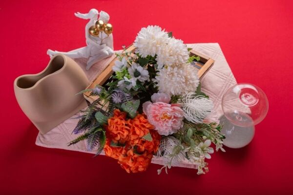 A luxury flower bouquet with beautiful white and pink flowers on a red backdrop.